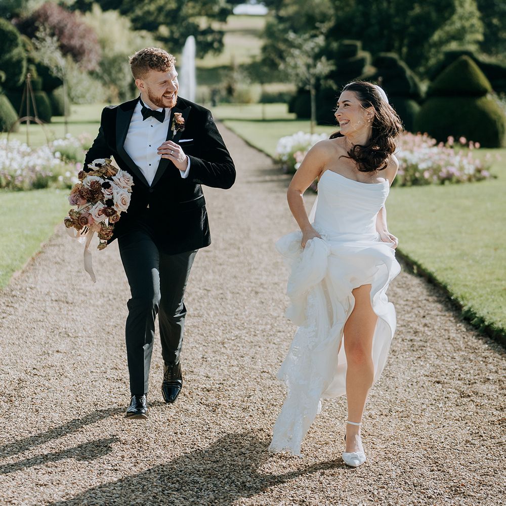 groom-in-black-tuxedo-running-with-bride-in-strapless-wedding-dress