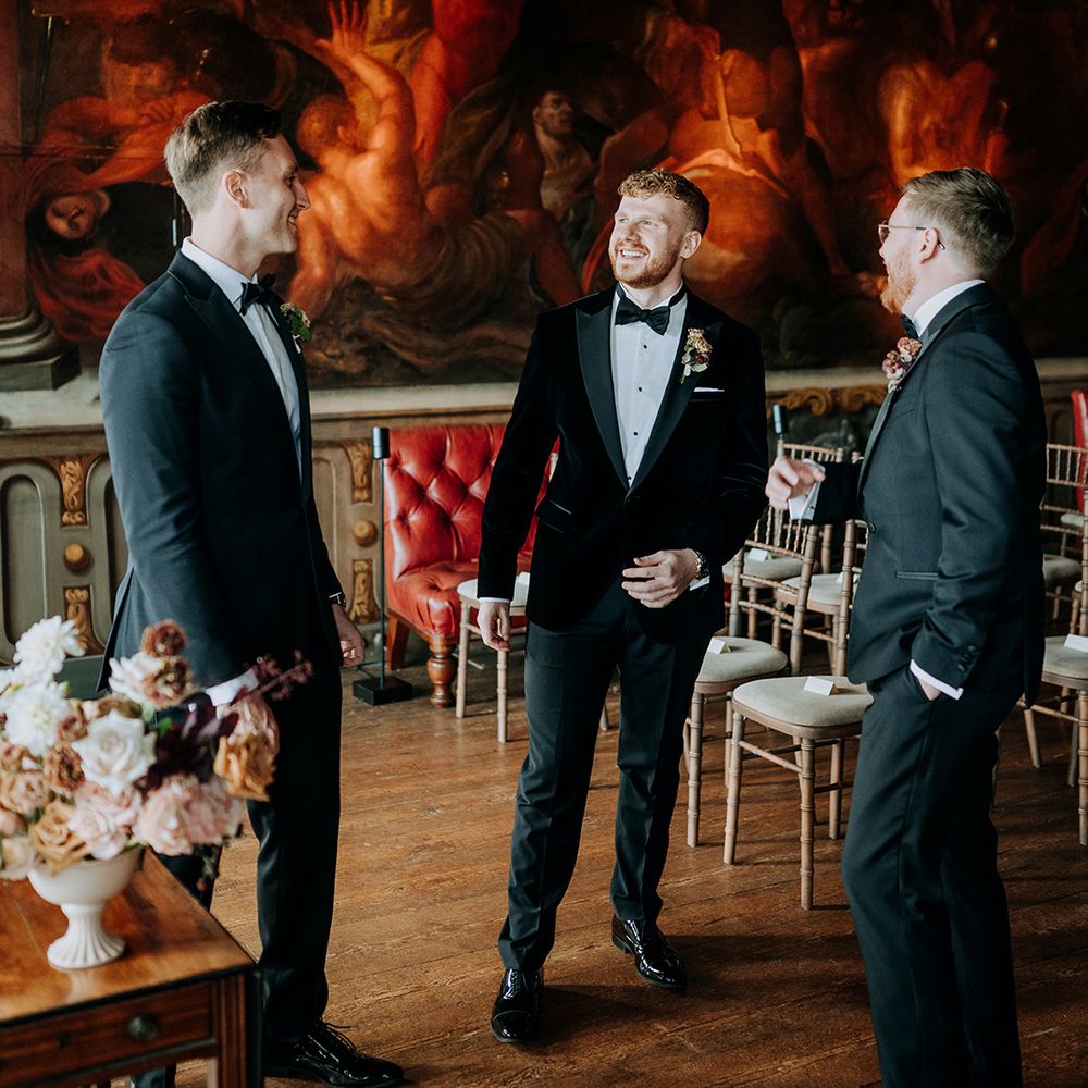 groom-with-groomsmen-in-black-tuxedos-at-ceremony-room