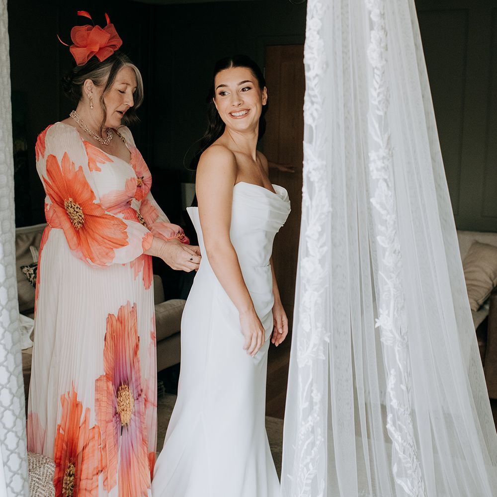 mother-of-the-bride-doing-up-brides-wedding-dress