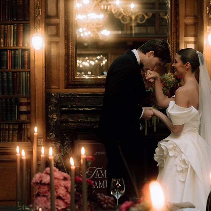 Groom kisses bride's hand at library wedding 