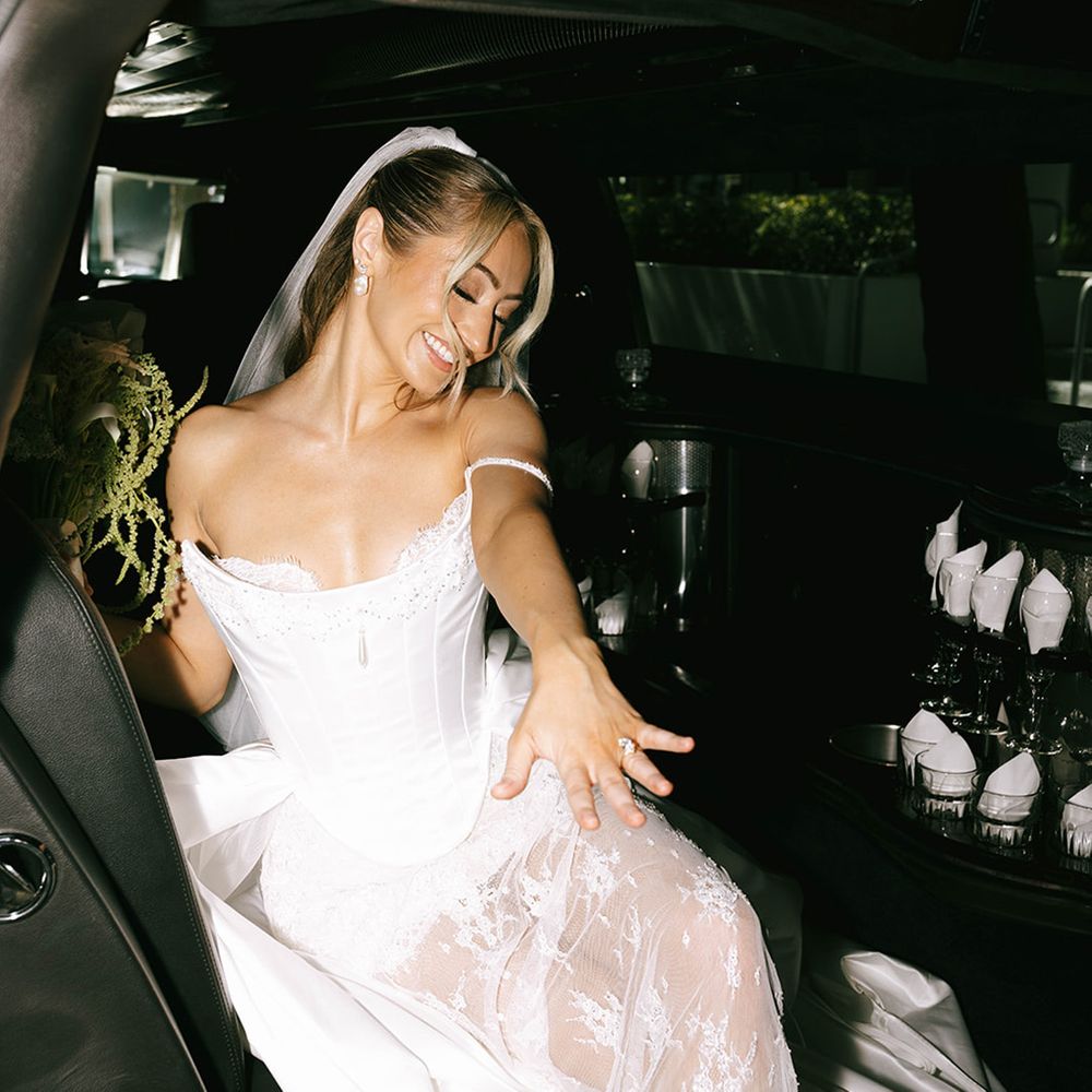 bride-in-wedding-car-wearing-bespoke-wedding-dress-showing-off-ring.
