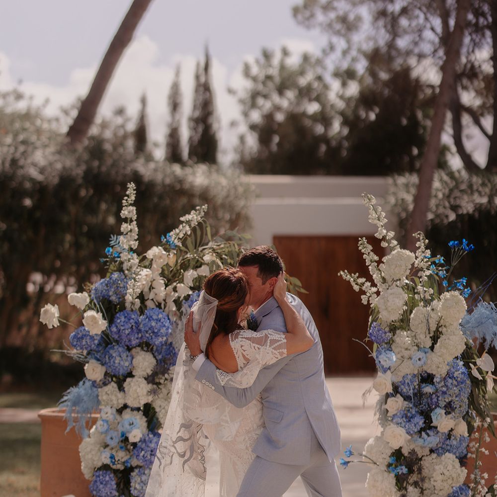 blue-wedding-flower-columns-with-bride-and-groom-having-first-kiss