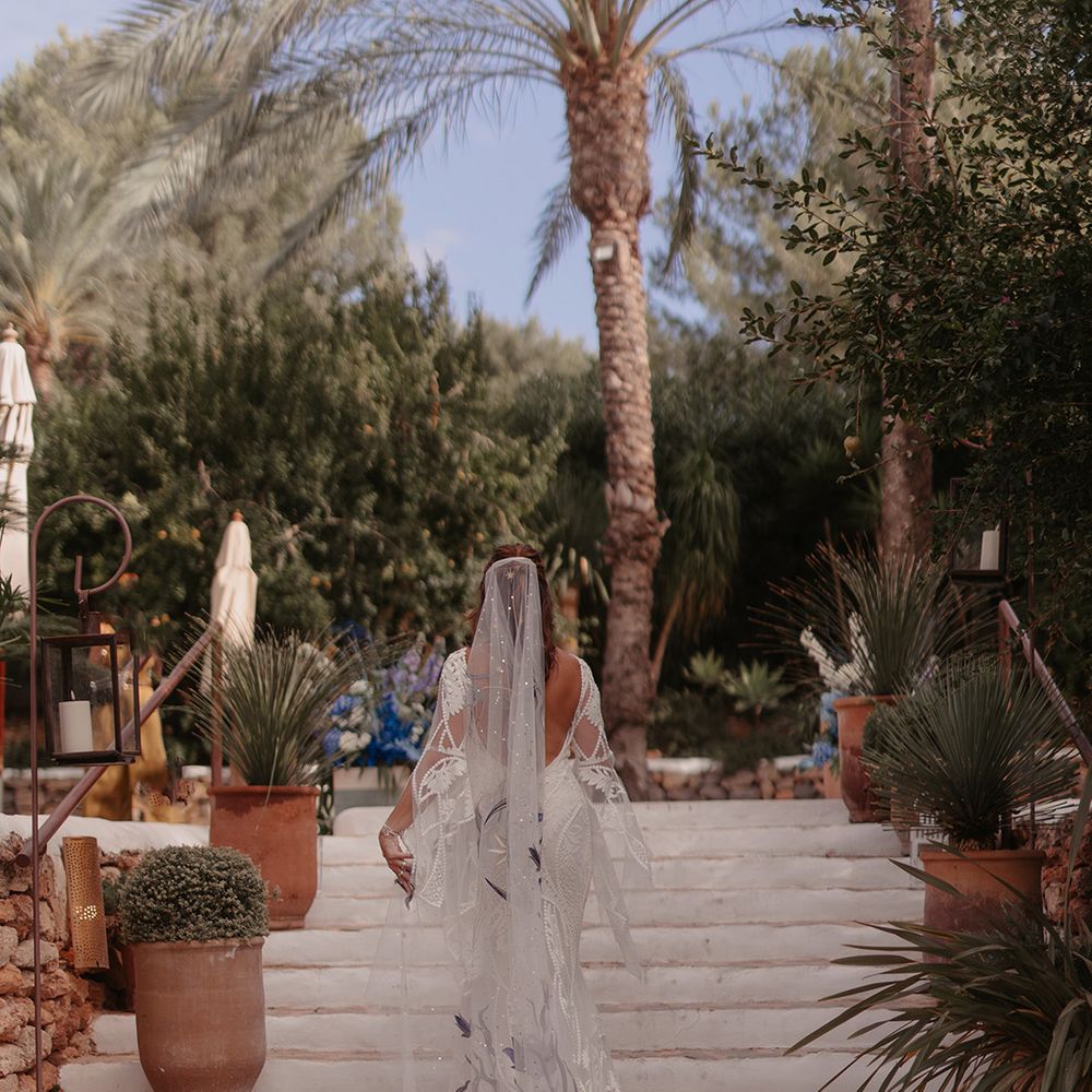 Bride in blue floral moon embroidered wedding veil walking up staircase