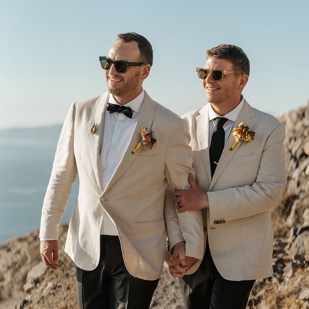 grooms-holding-hands-in-white-suits-with-sunglasses