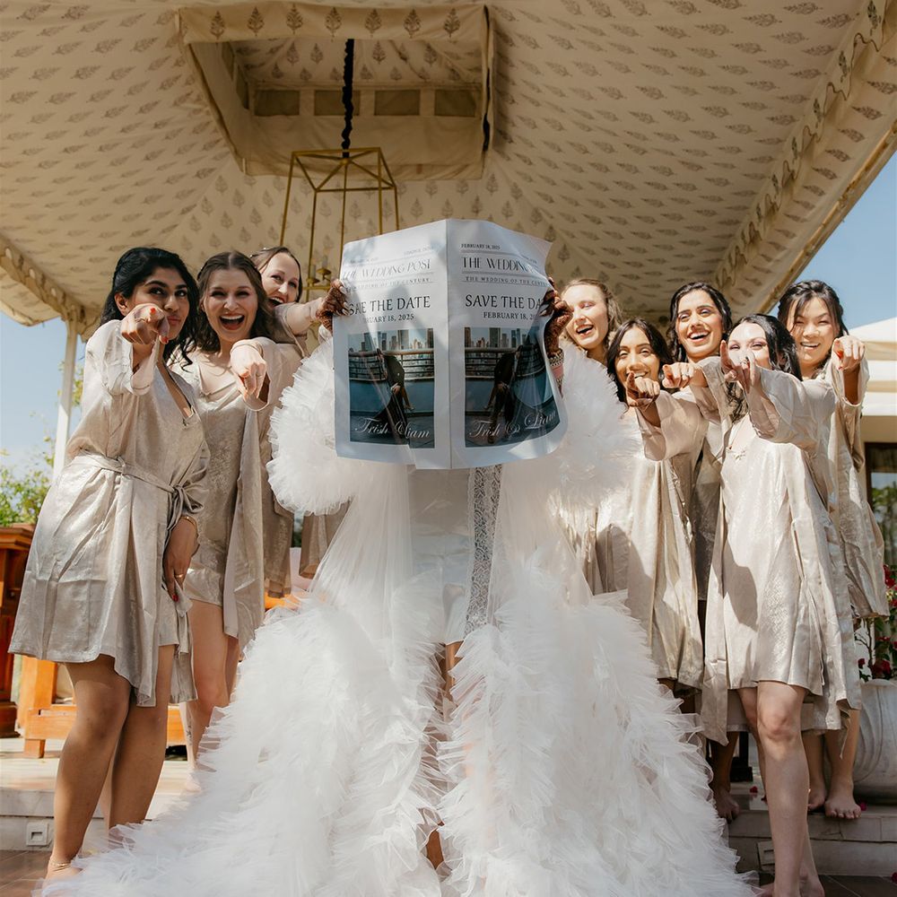 Bride reading from personalised newspaper in tulle robe with bridal party in matching pyjamas