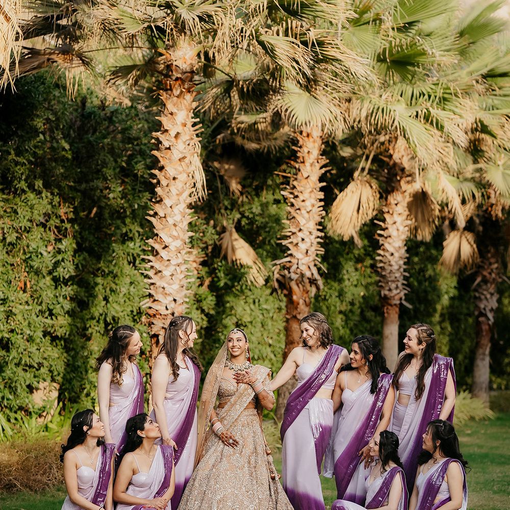 Bride in gold wedding outfits with bridal party in purple sarees