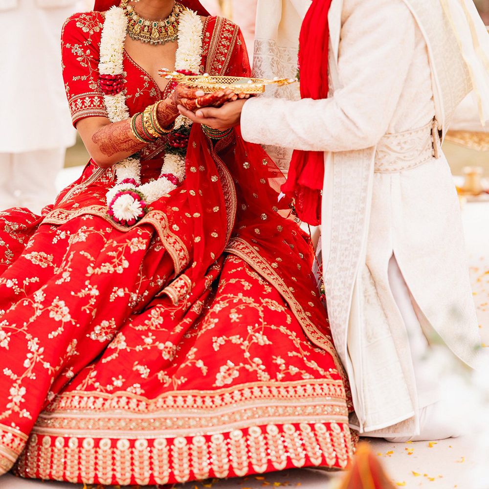 groom-in-white-sherwani-with-bride-in-red-and-gold-lehenga