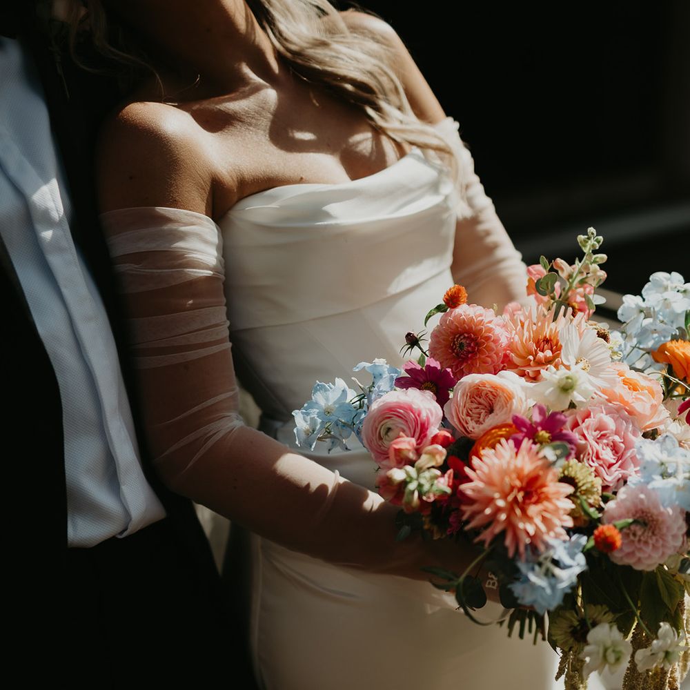 bride-in-strapless-wedding-dress-with-mesh-sleeves-and-colourful-bouquet