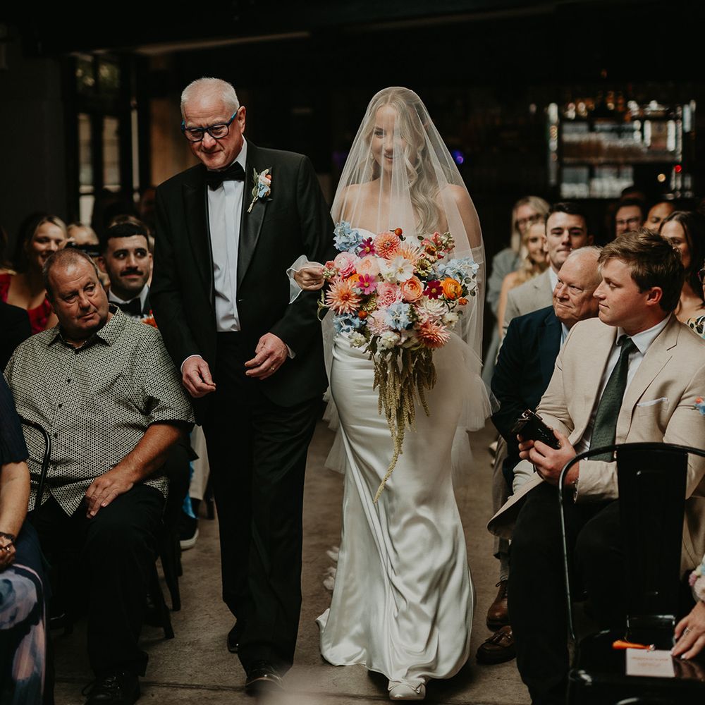 father-of-the-bride-and-bride-walks-down-the-aisle-at-industrial-wedding-venue