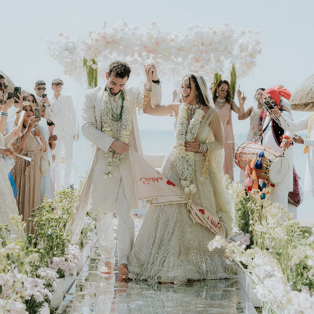 Couple walks back down mirrored aisle as married couple for beach wedding