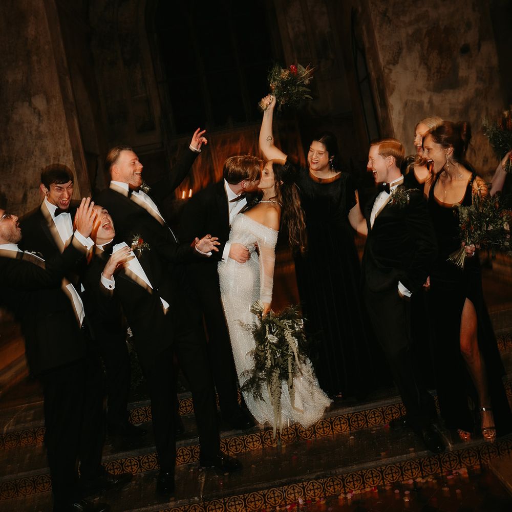 bride-and-groom-kiss-as-wedding-party-celebrates