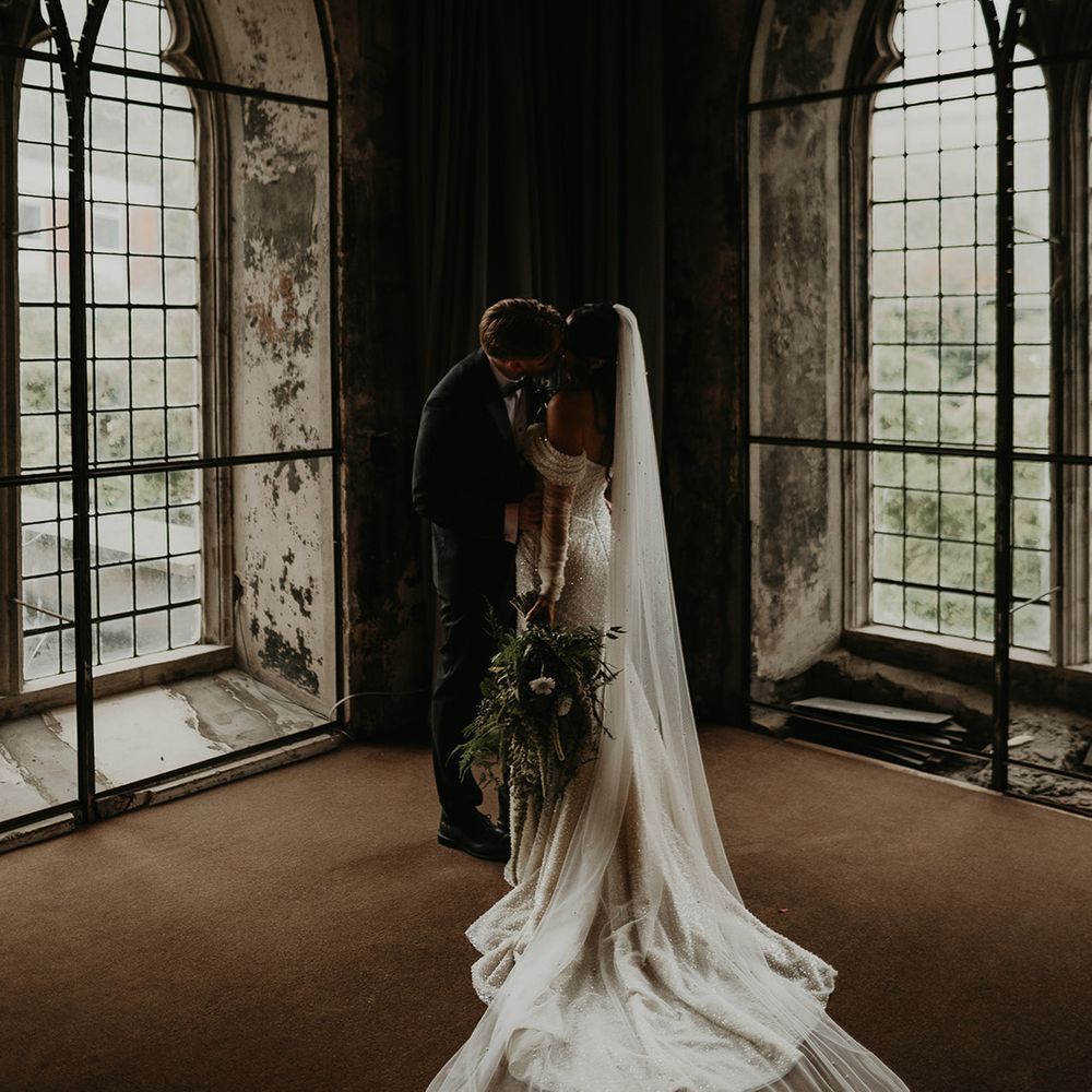 couple-kisses-at-beautiful-wedding-venue-with-large-windows