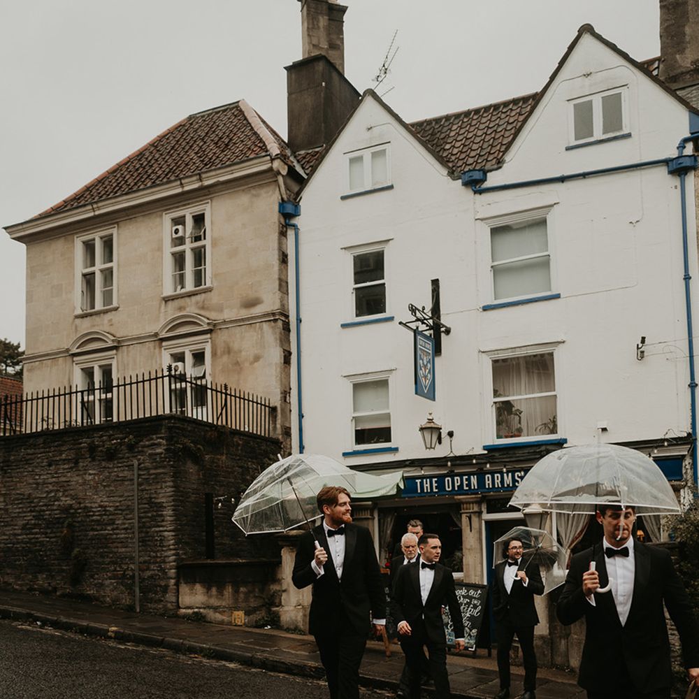 groom-and-groomsmen-walking-under-clear-umbrellas