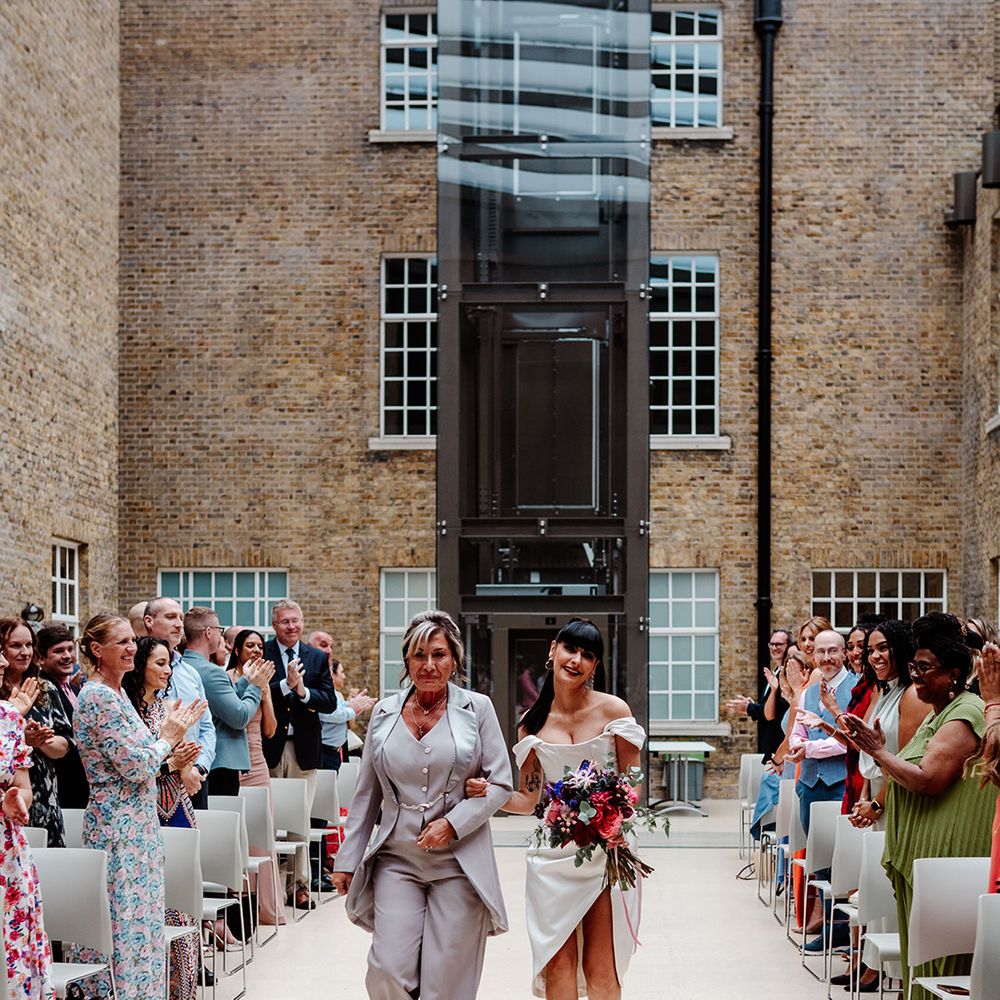 bride-in-short-wedding-dress-walks-down-the-aisle-with-mother