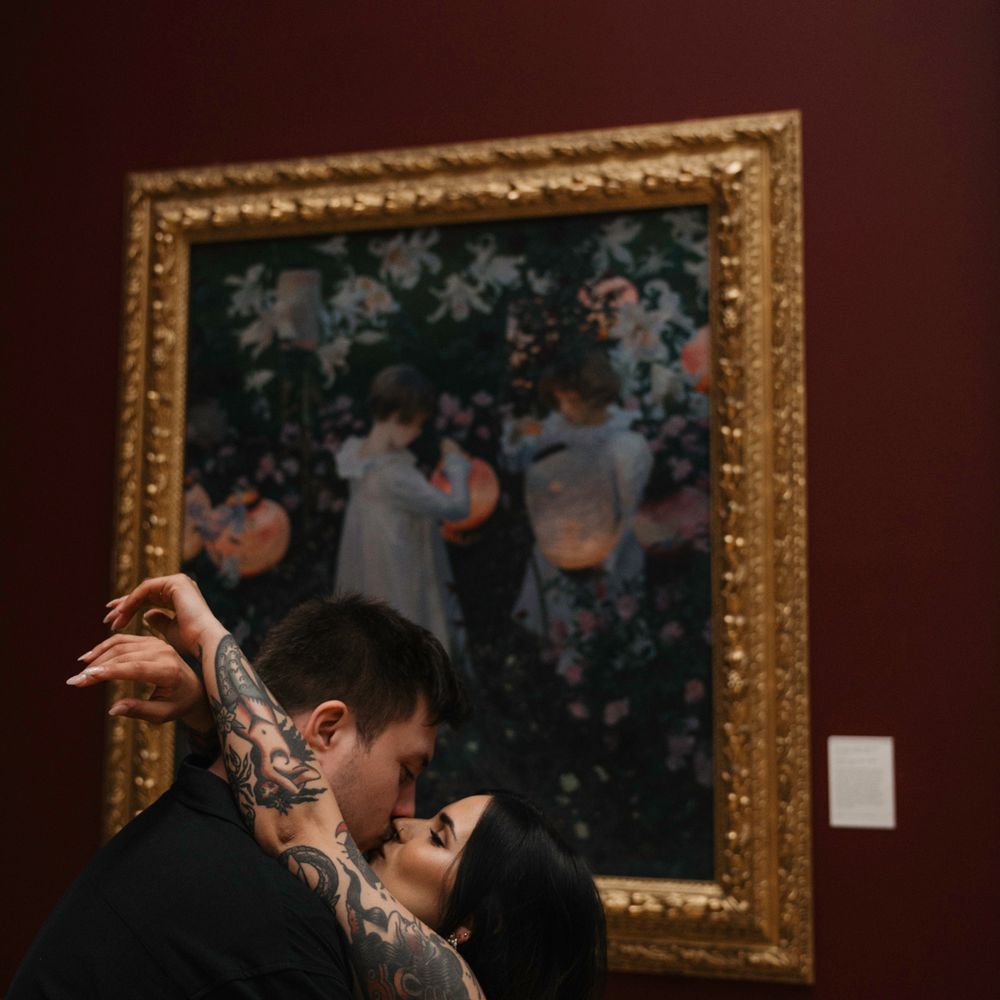 Couple kisses in front of painting 
