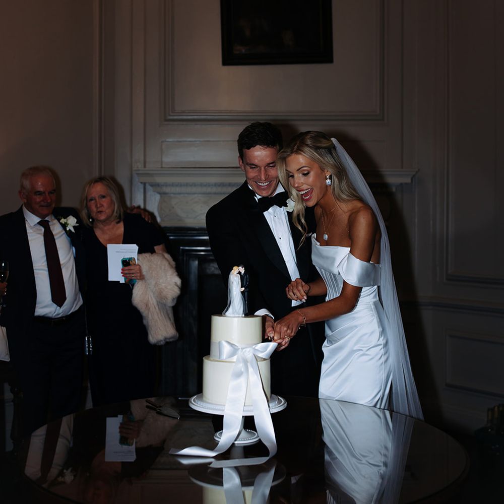 bride-and-groom-cut-classic-white-iced-two-tier-wedding-cake-with-ribbon