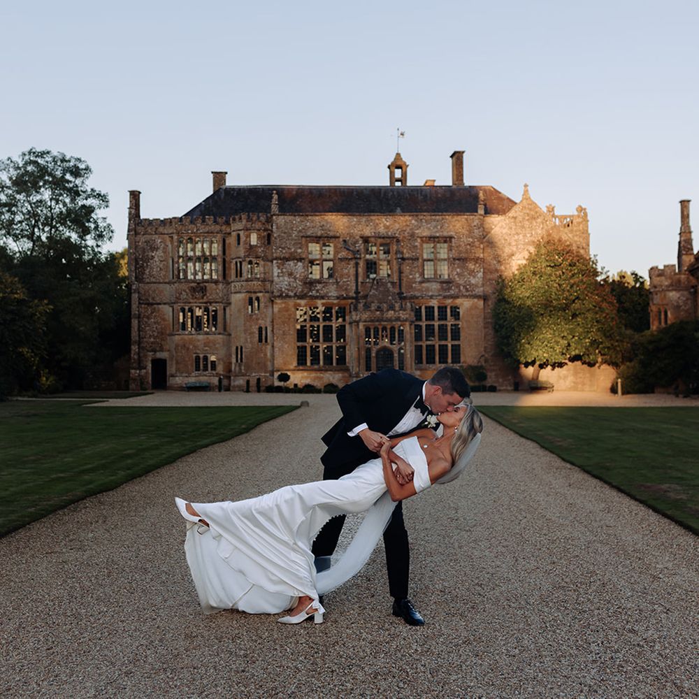 groom-kisses-bride-in-romantic-kiss-in-front-of-country-house-wedding-venue