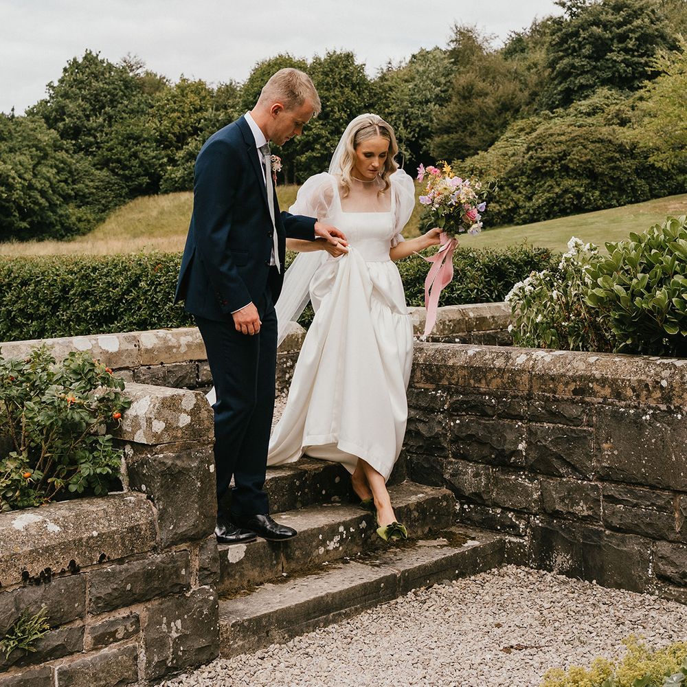 groom-in-blue-wedding-suit-walks-bride-down-steps