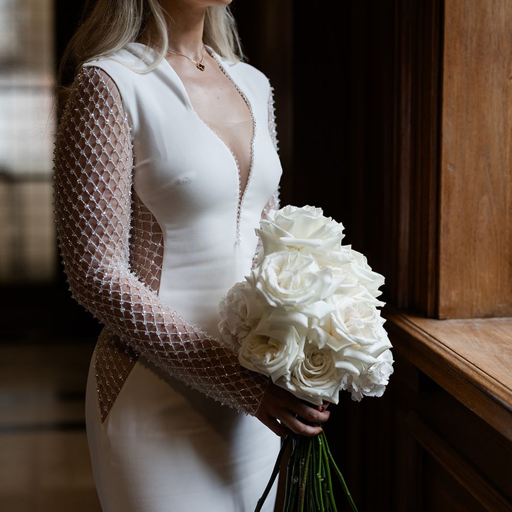 bride-in-long-sleeve-sparkly-wedding-dress-with-white-rose-bouquet