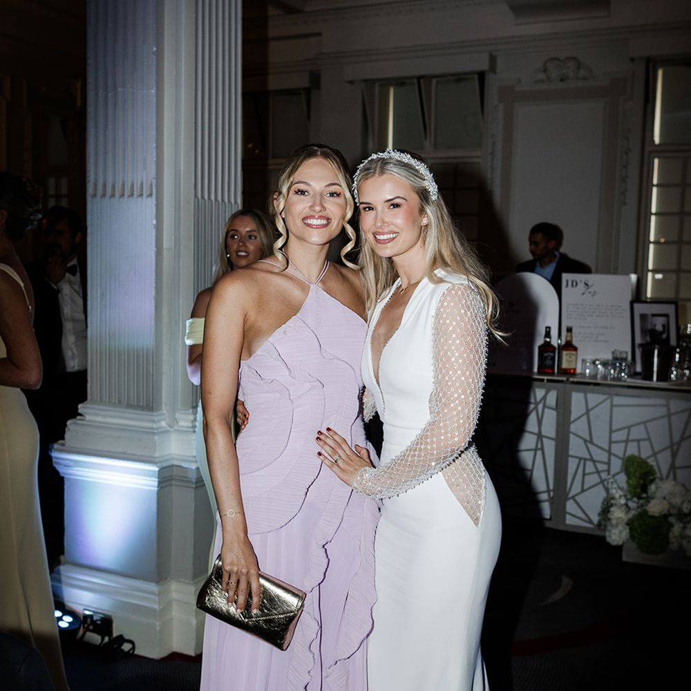 bride-poses-with-wedding-guest-in-lilac-dress