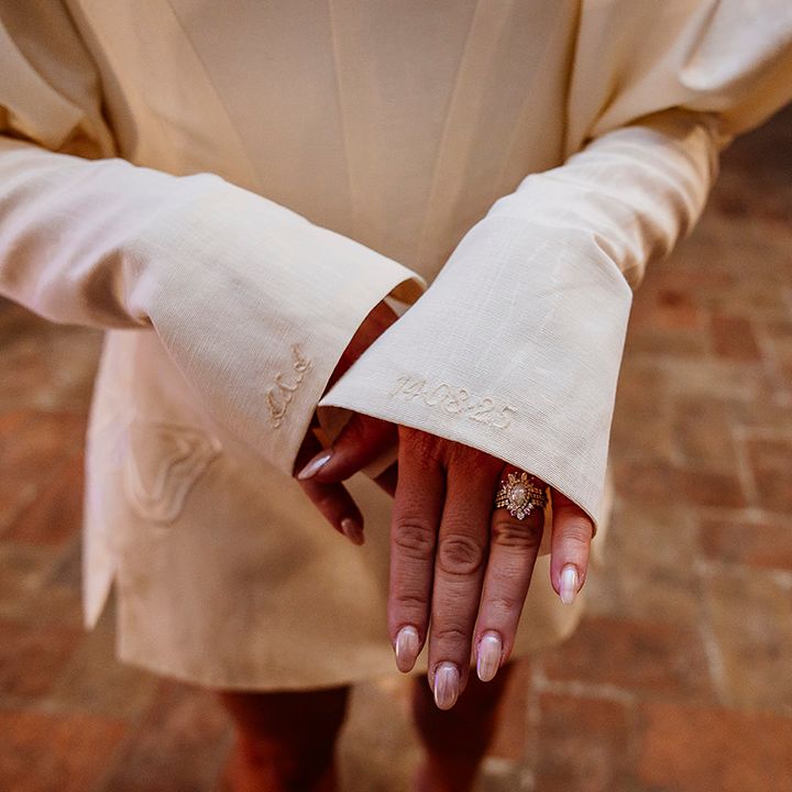 bride-showing-off-unique-art-deco-inspired-engagement-ring-with-embroidered-sleeves