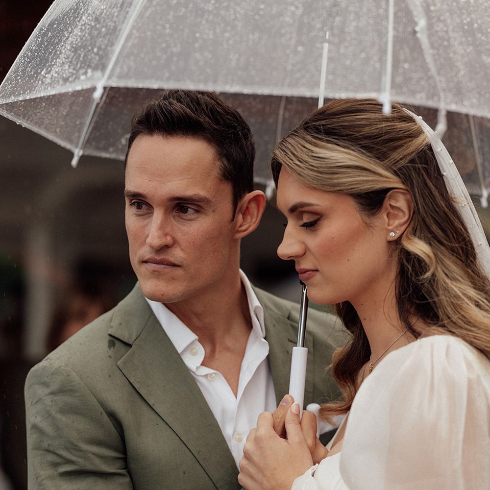 couple-under-umbrella-during-rainy-outdoor-ceremony