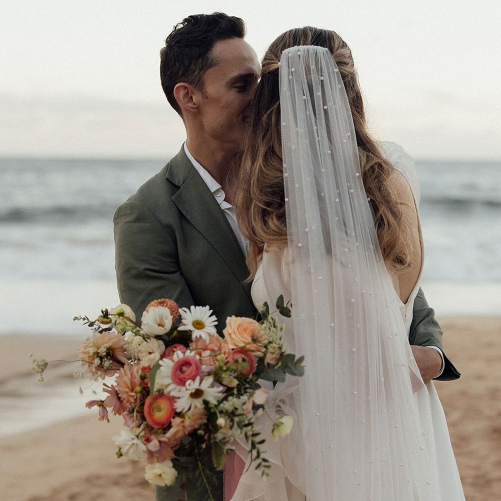 groom-kisses-bride-on-cheek-wearing-pearl-veil