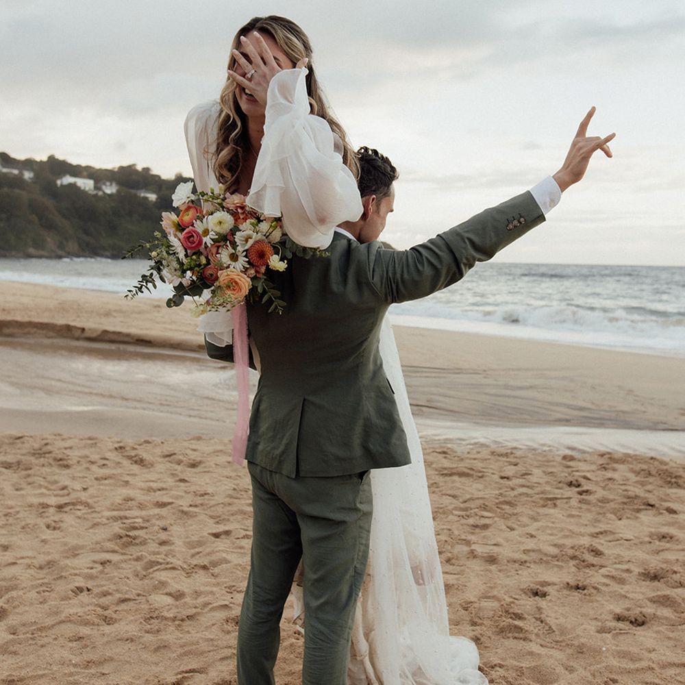groom-lifts-bride-over-shoulder-on-beach-wedding