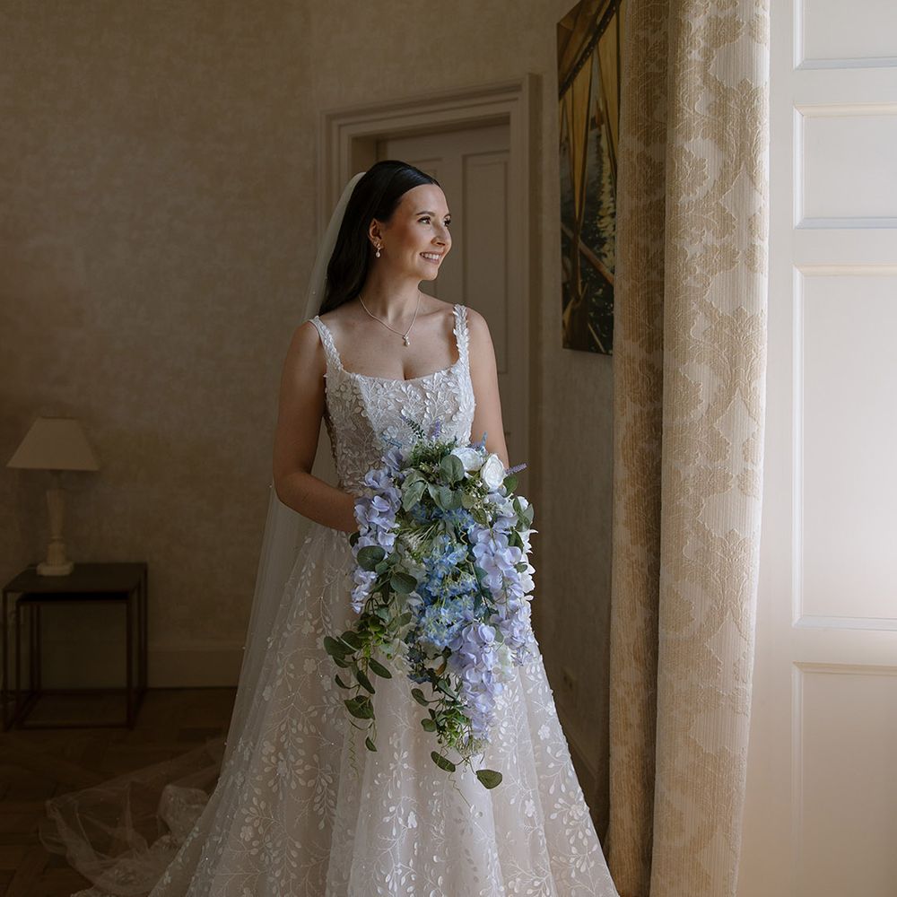 Bride in floral patterned wedding dress with blue cascading bouquet