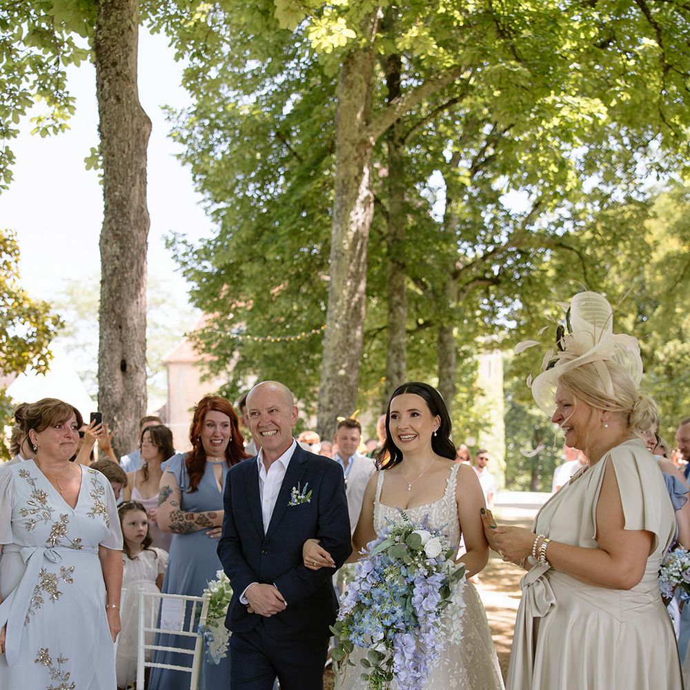 Bride walking down the aisle with father of the bride in navy suit