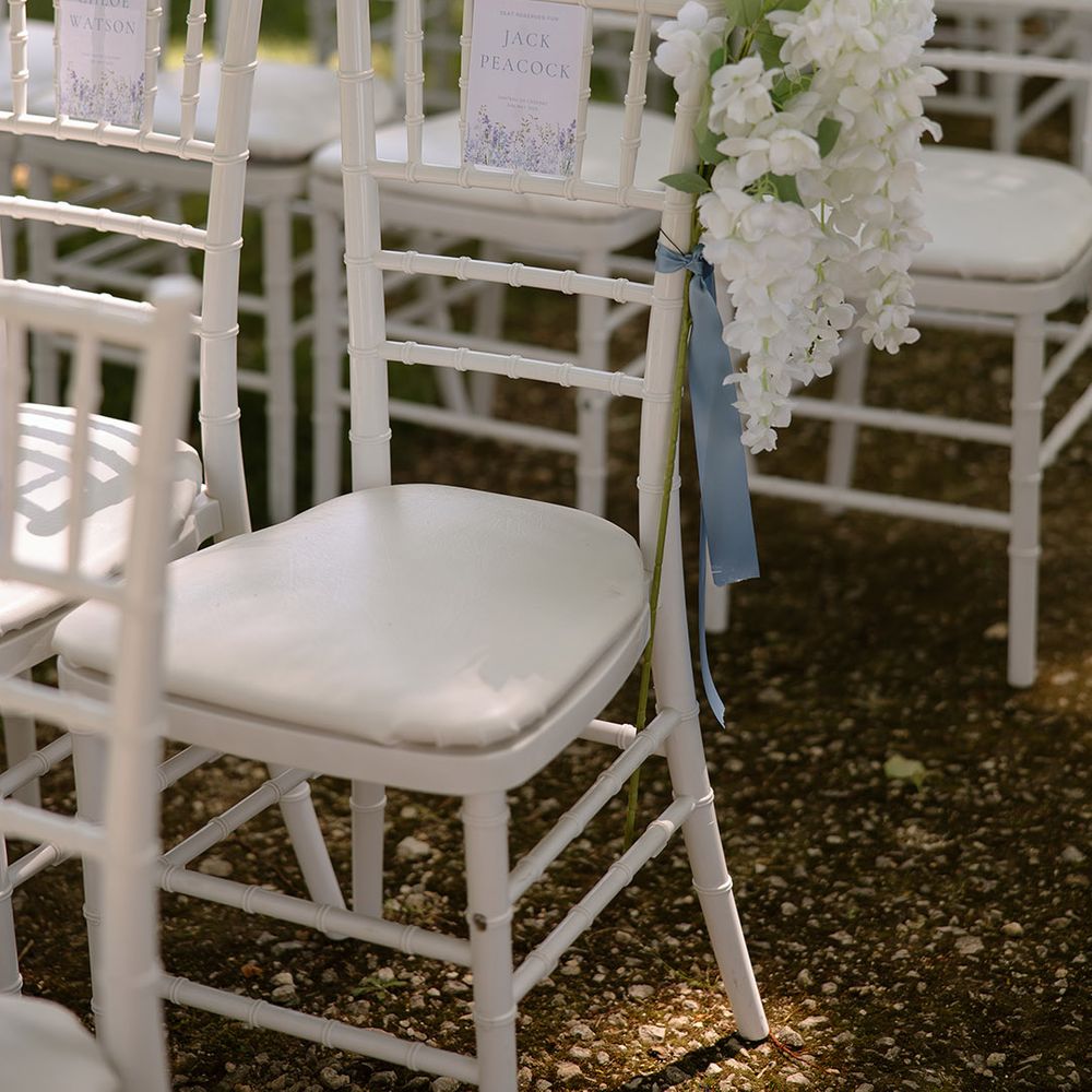 White flowers with blue ribbon decorating the chairs