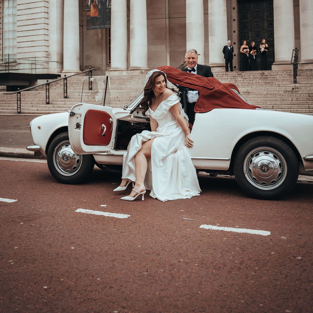 Bride gets out of white convertible wedding car
