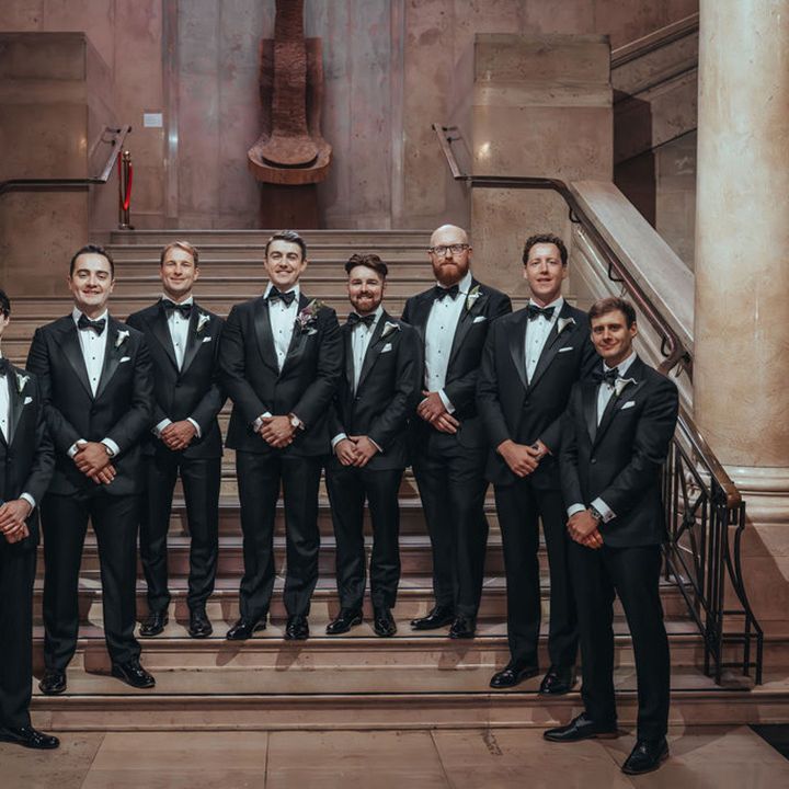 Groomsmen and groom standing together in black tuxedos