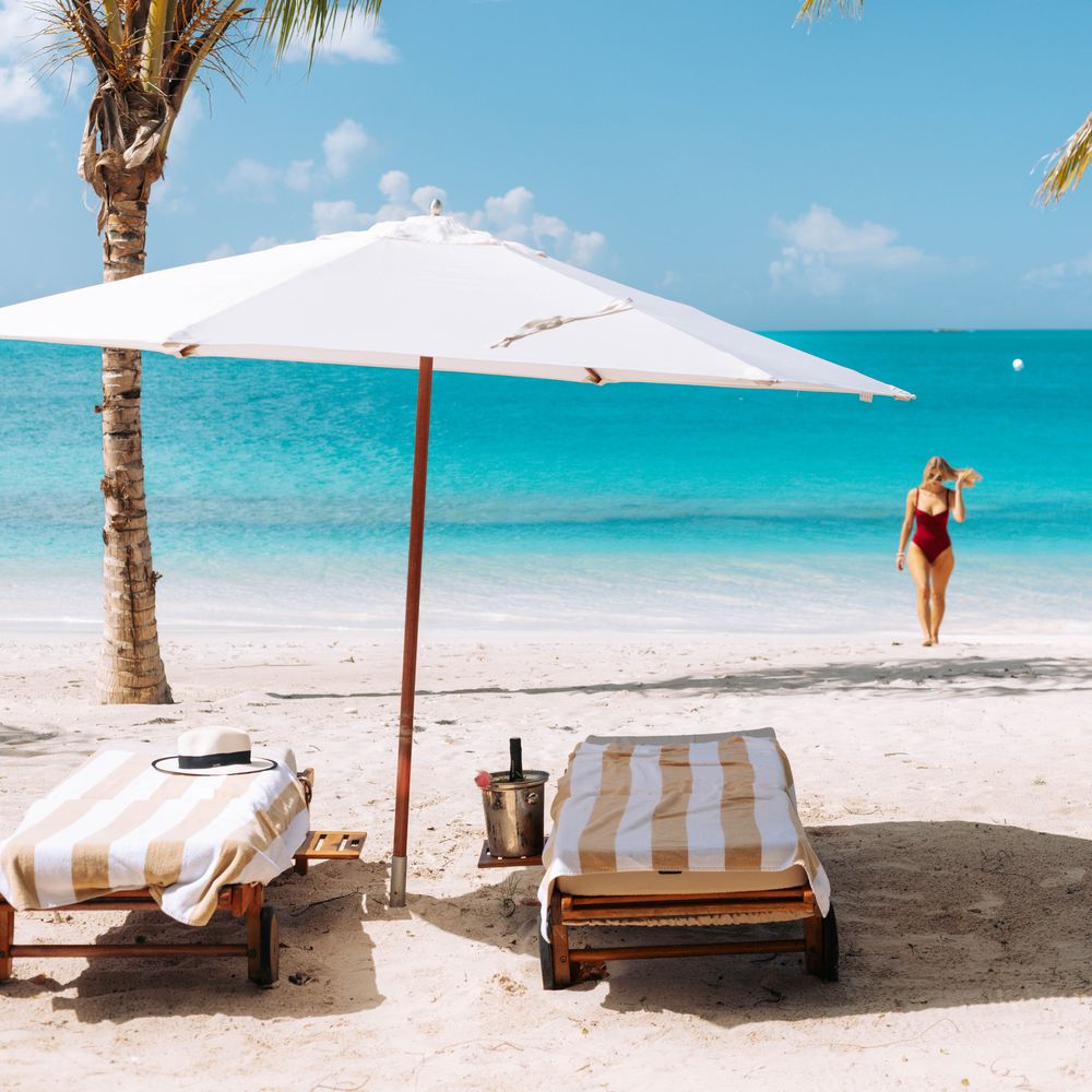 Hermitage Bay with sun loungers on beach under umbrella