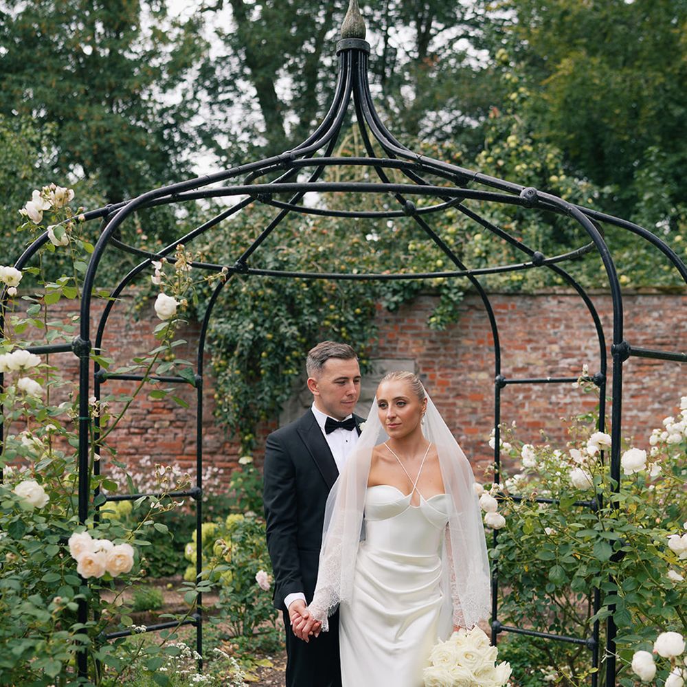 Bride in halter neck satin wedding dress with groom in black tuxedo
