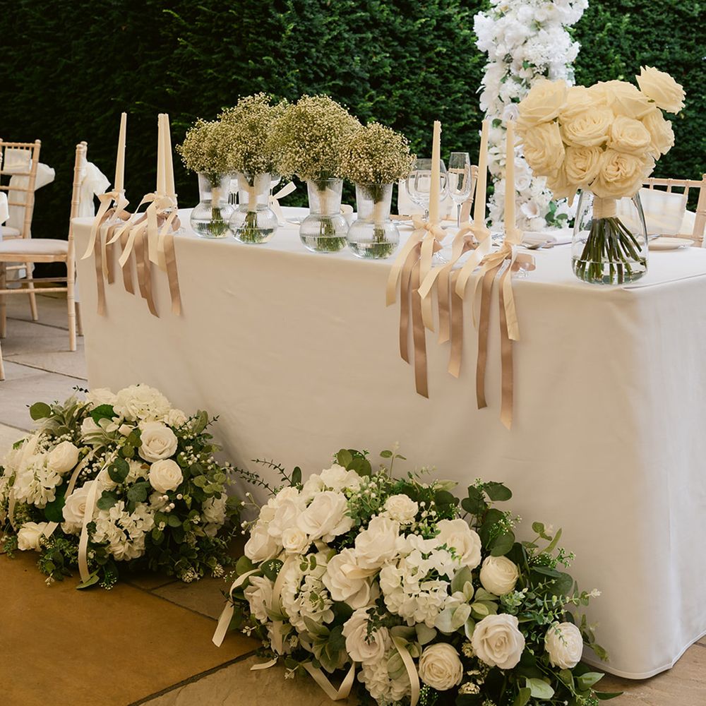 White sweetheart table for marquee wedding with white flowers
