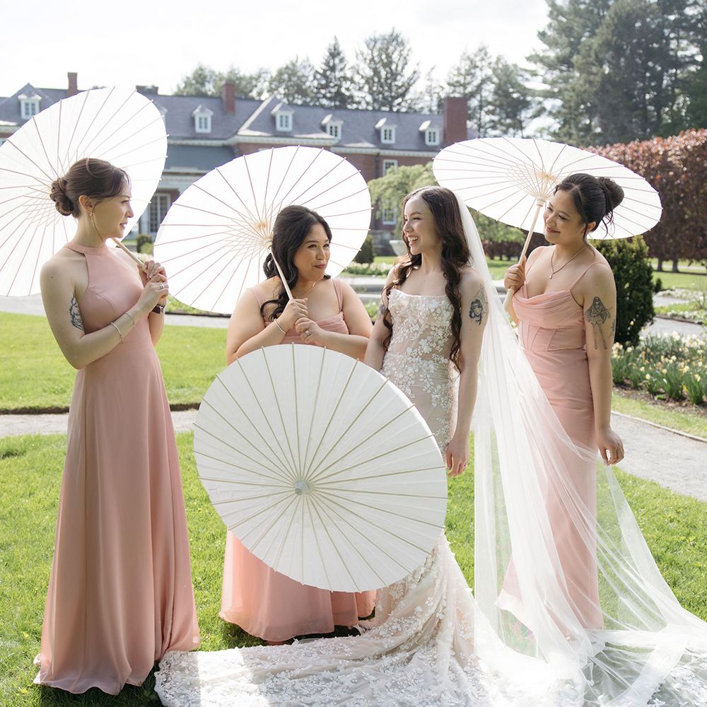 Bridesmaids wearing pink bridesmaid dresses with paper umbrellas
