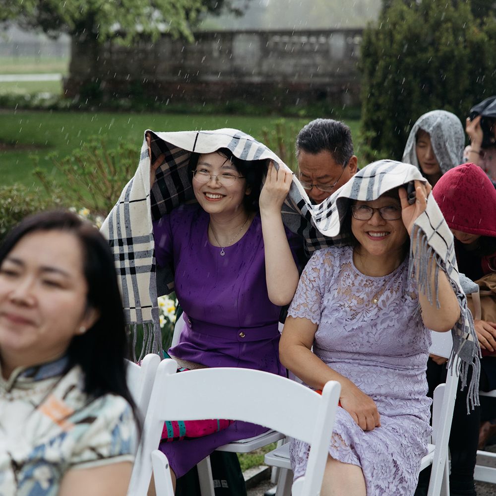 Guests hide under jackets from the rain 