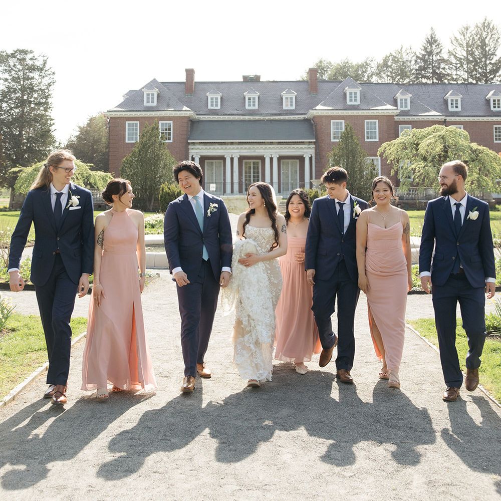 Wedding party walking with country house venue backdrop