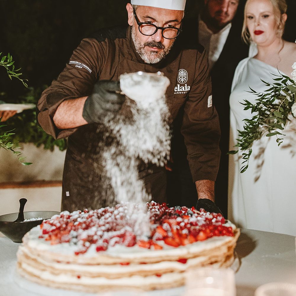 Chef dusts icing sugar over millefoglie wedding cake 