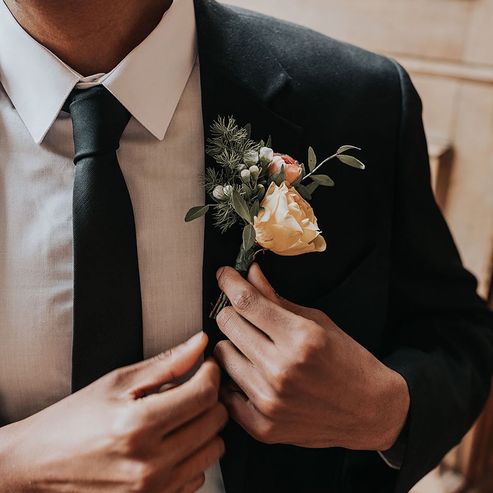 Groom wearing black wedding tie and orange buttonhole