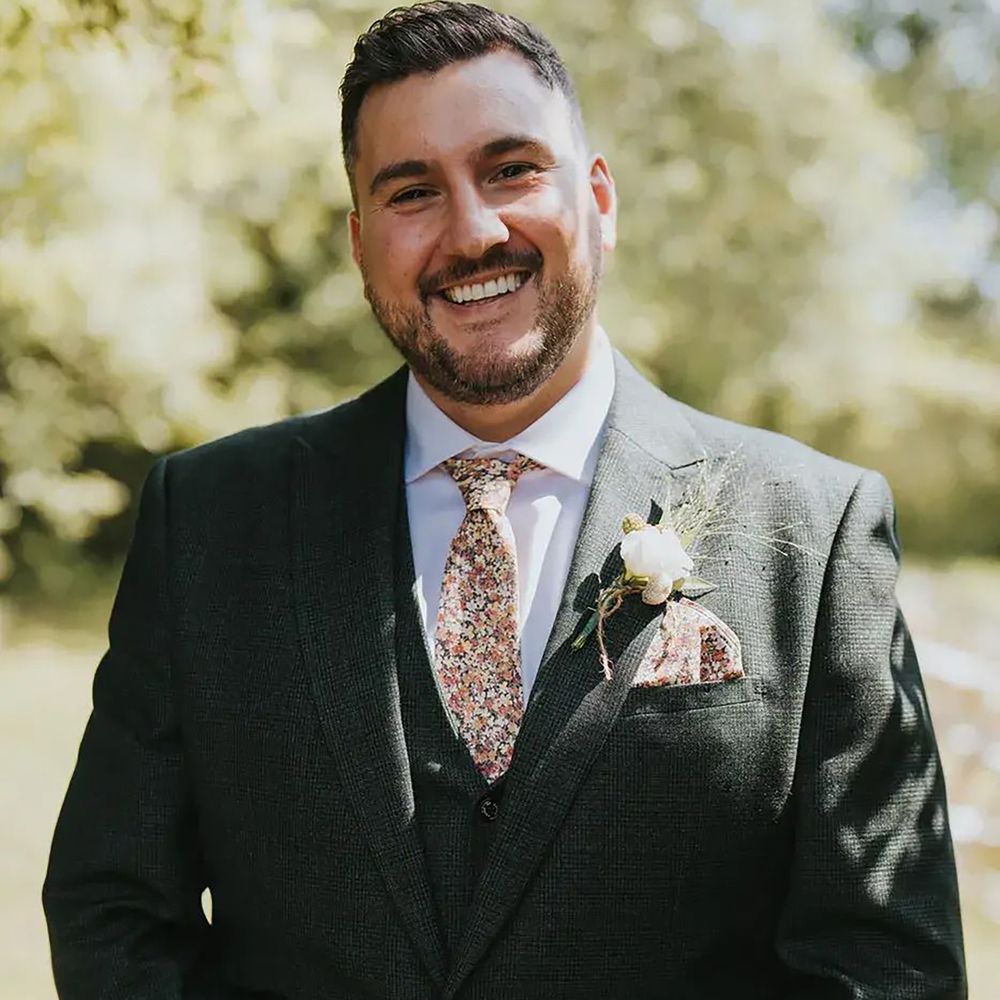 Groom wearing floral patterned wedding tie and dark green suit