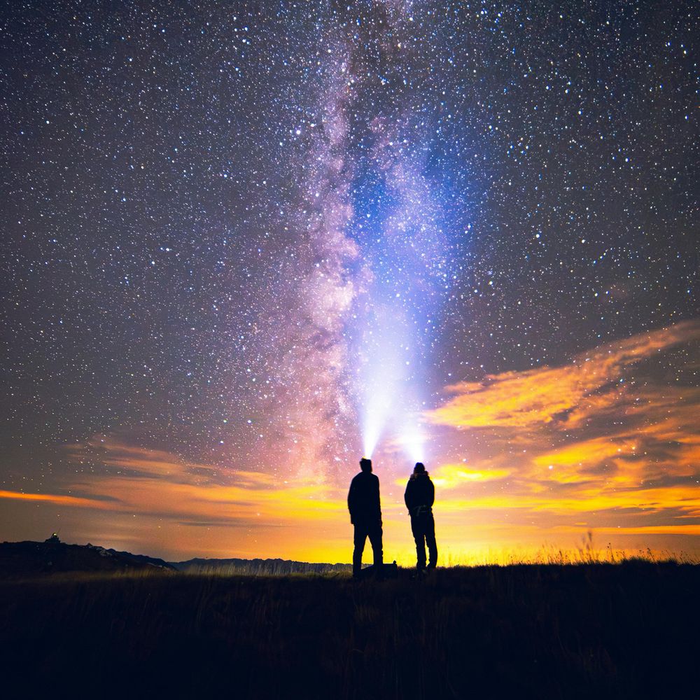 Couple stands looking up at the Milky Way galaxy