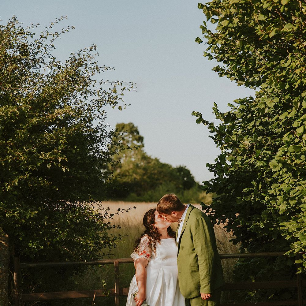 Groom in green wedding suit kissing the bride 