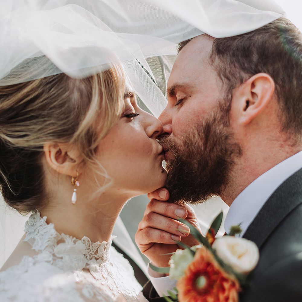 Couple kisses under wedding veil 