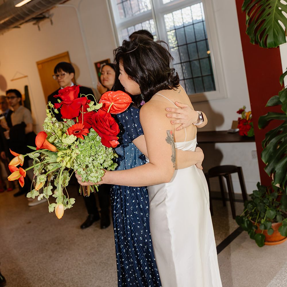 bride greeting guests with red bouquet