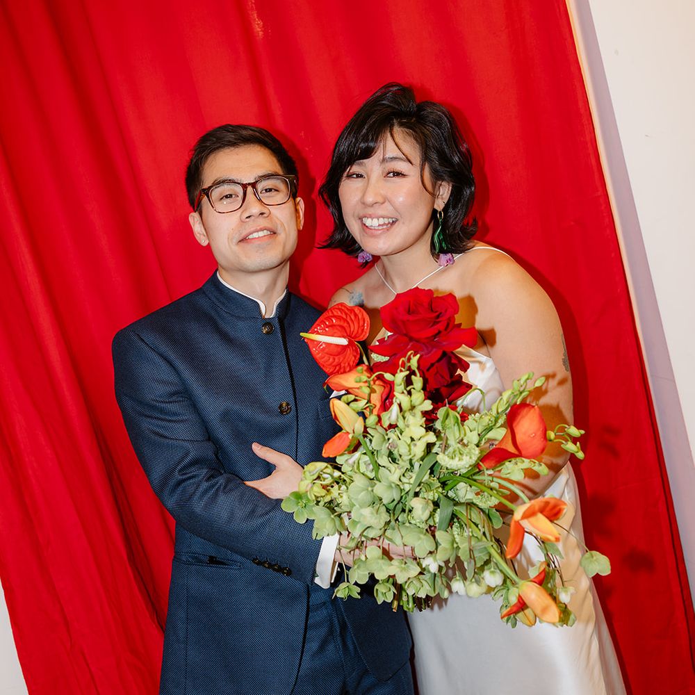 bride and groom pose with red backdrop decor