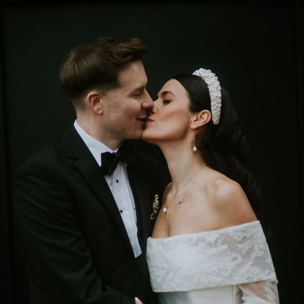married couple kiss bride in pearl headband