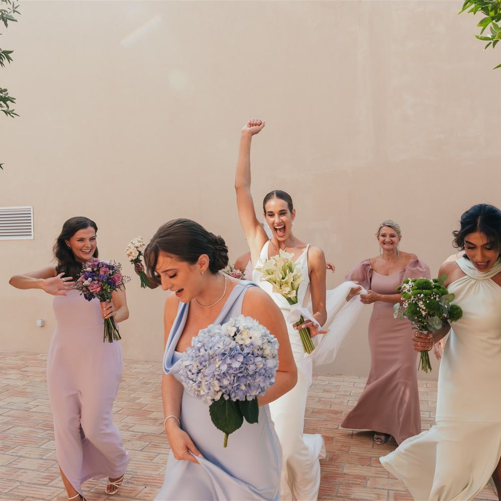 bridesmaids run laughing pastel dresses