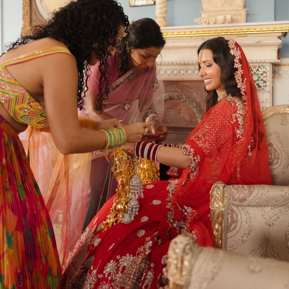 bride getting ready in traditional red and gold saree